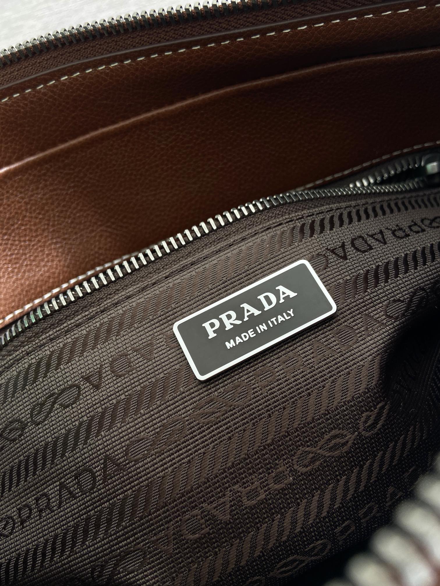Prada logo label on brown monogram interior zip pocket, 'Made in Italy' tag