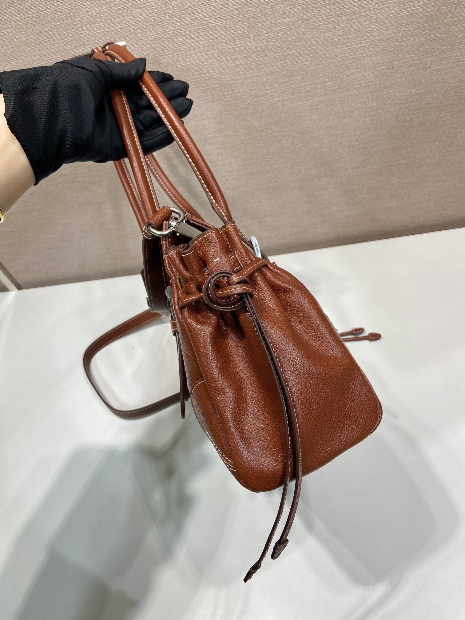 Prada brown leather tote bag side view with zip top and adjustable shoulder strap