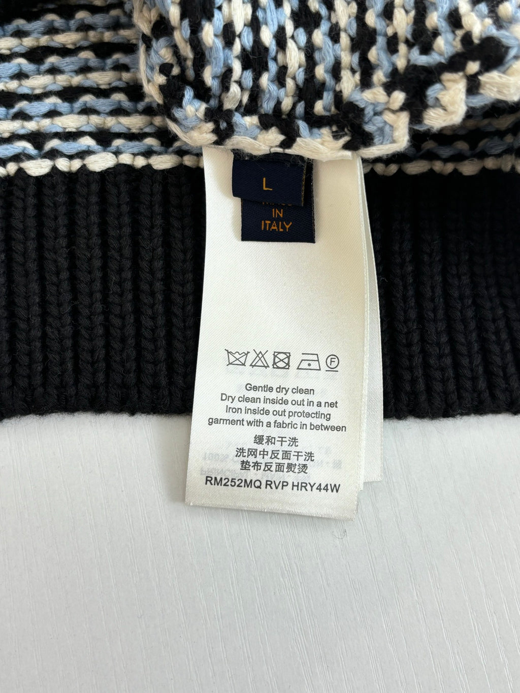 Size L care label on houndstooth sweater, washing instructions and materials tag