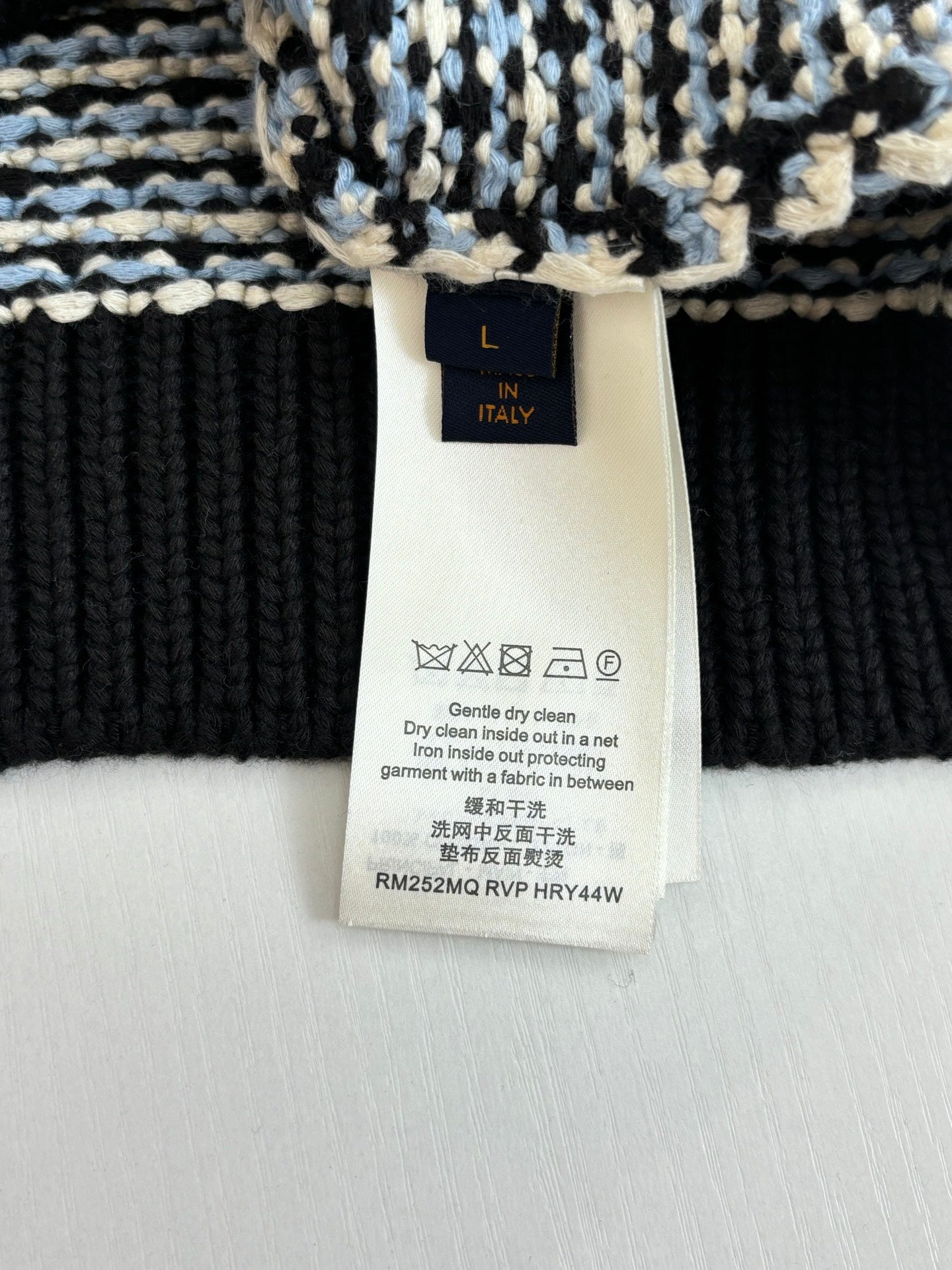 Size L care label on houndstooth sweater, washing instructions and materials tag
