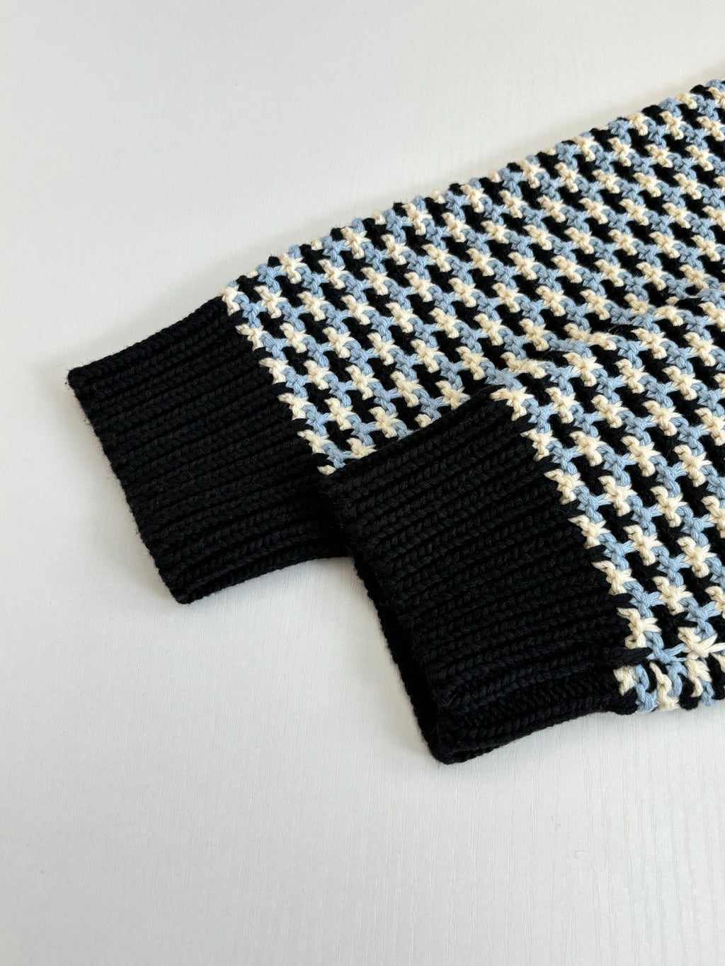 Ribbed cuffs and hem of houndstooth sweater, black knit with cream/blue grid