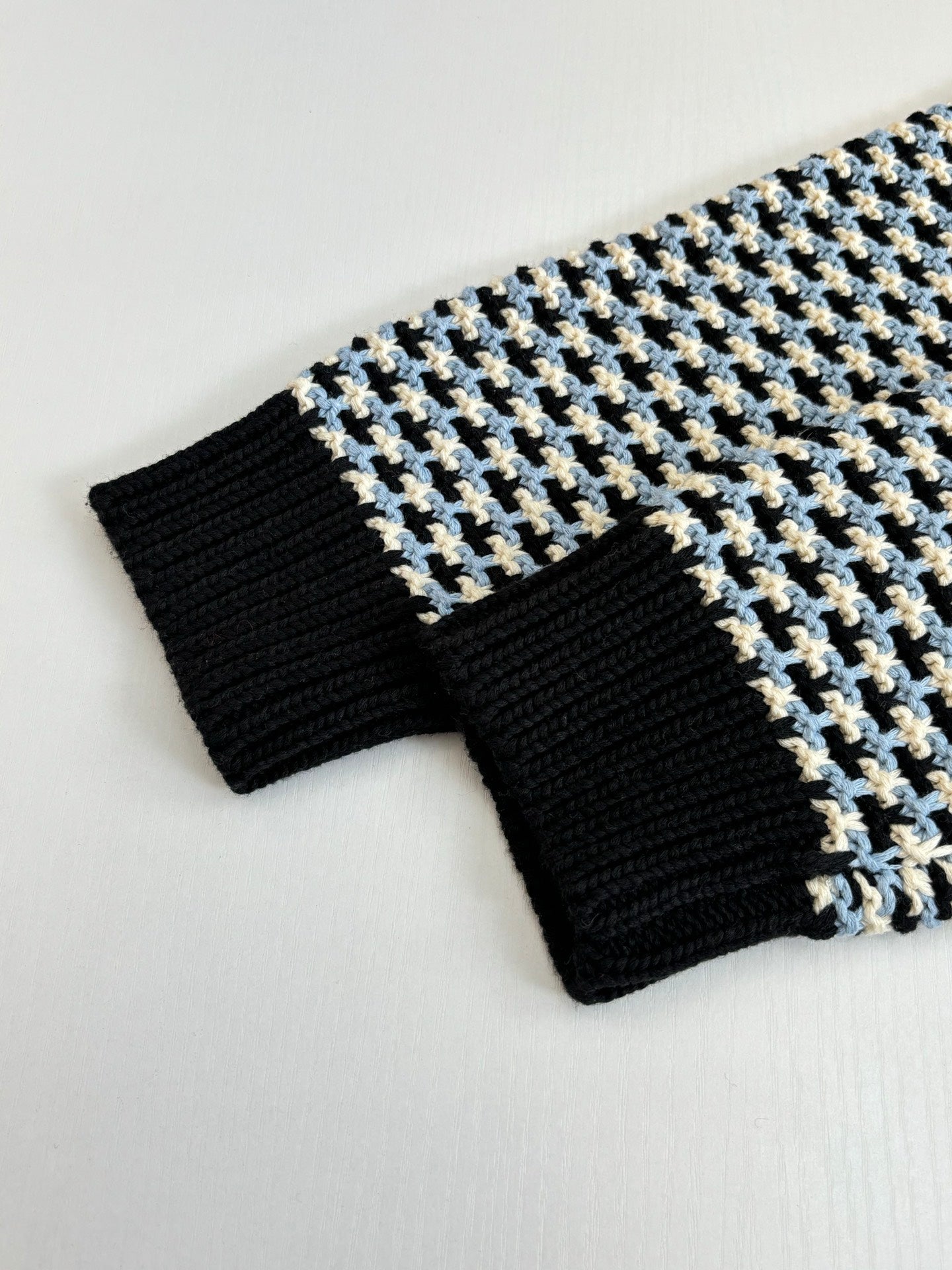 Ribbed cuffs and hem of houndstooth sweater, black knit with cream/blue grid