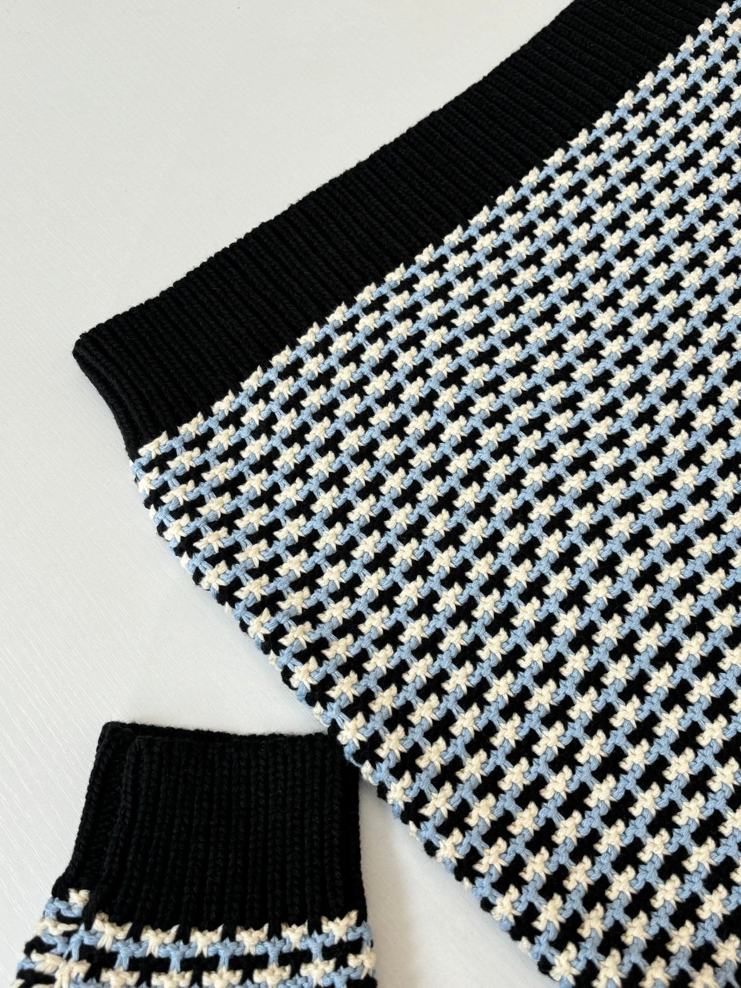 Houndstooth knit sleeve with black rib cuff, cream/blue grid pattern