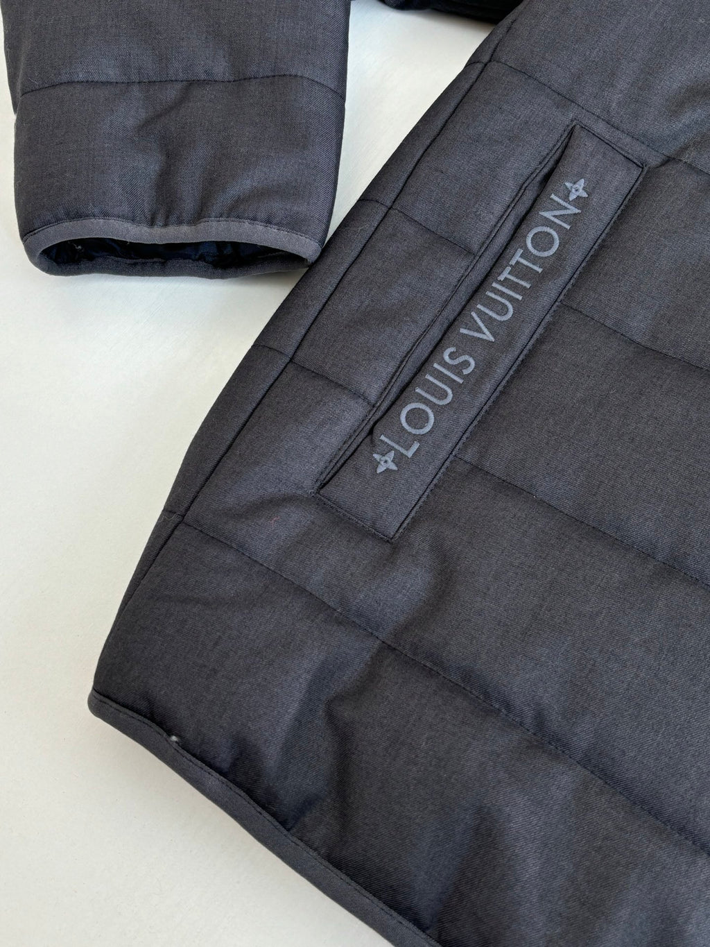 Dark navy puffer jacket sleeve detail with Louis Vuitton printed strap