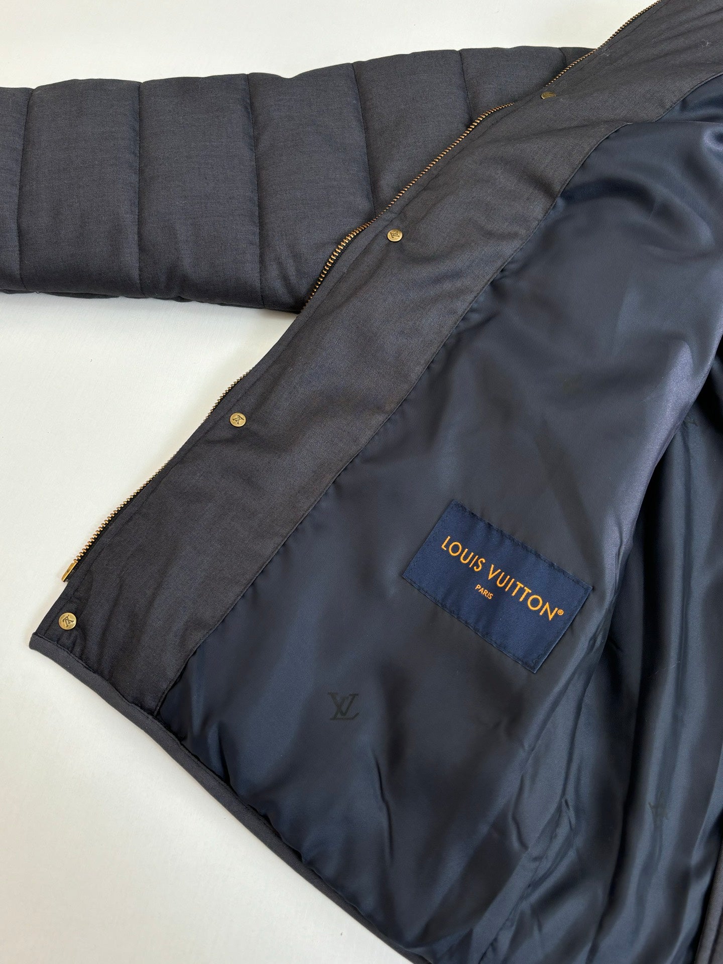 Dark navy puffer jacket sleeve with Louis Vuitton logo patch