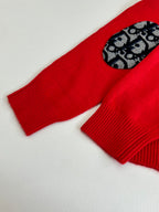 Red knit sweater sleeve with black-and-blue logo-pattern oval detail
