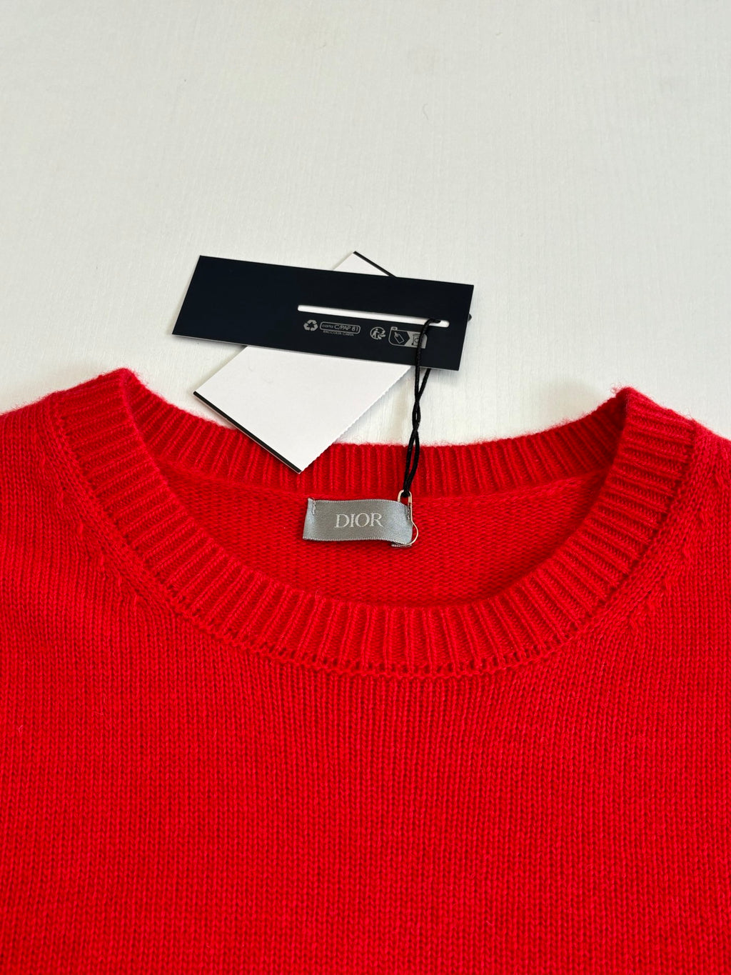 Red knit sweater neckline with Dior tag and care label inside collar
