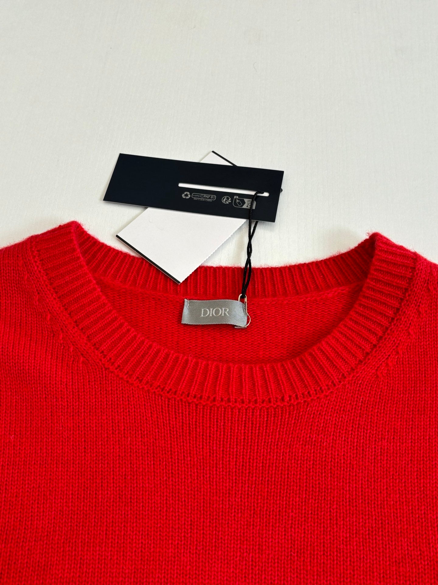 Red knit sweater neckline with Dior tag and care label inside collar