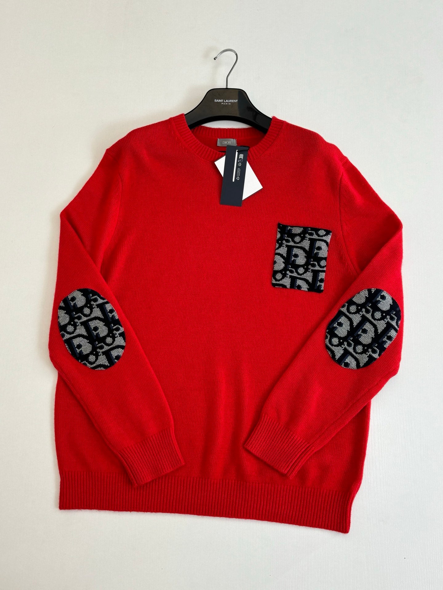 Red knit long-sleeve sweater with ribbed collar, pocket patch, and logo-pattern sleeves