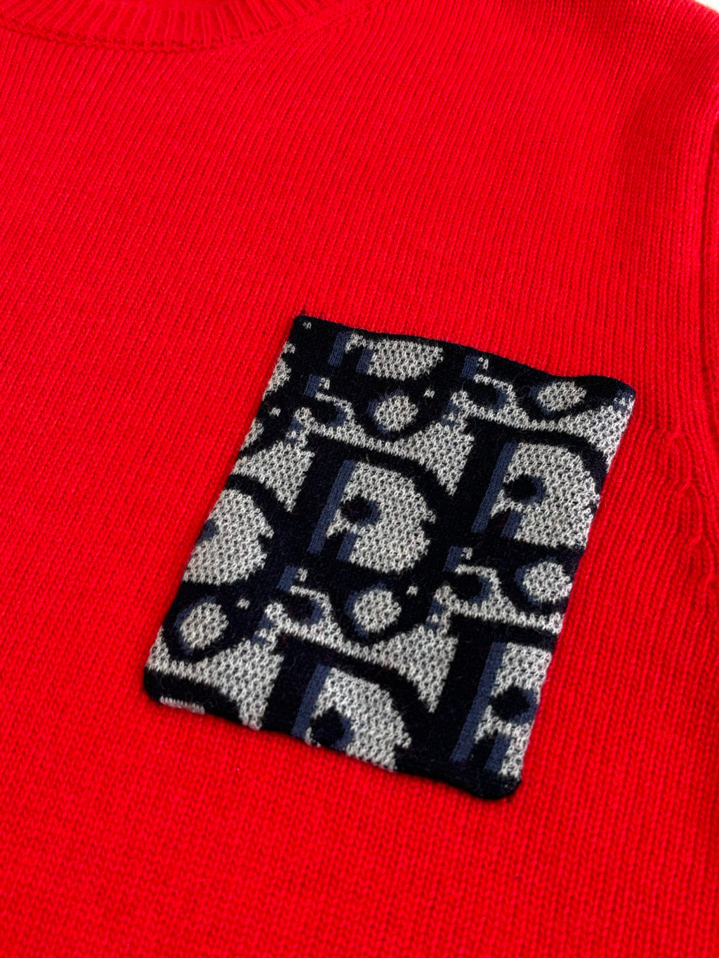 Red knit sweater with black-and-blue logo pattern patch on the chest