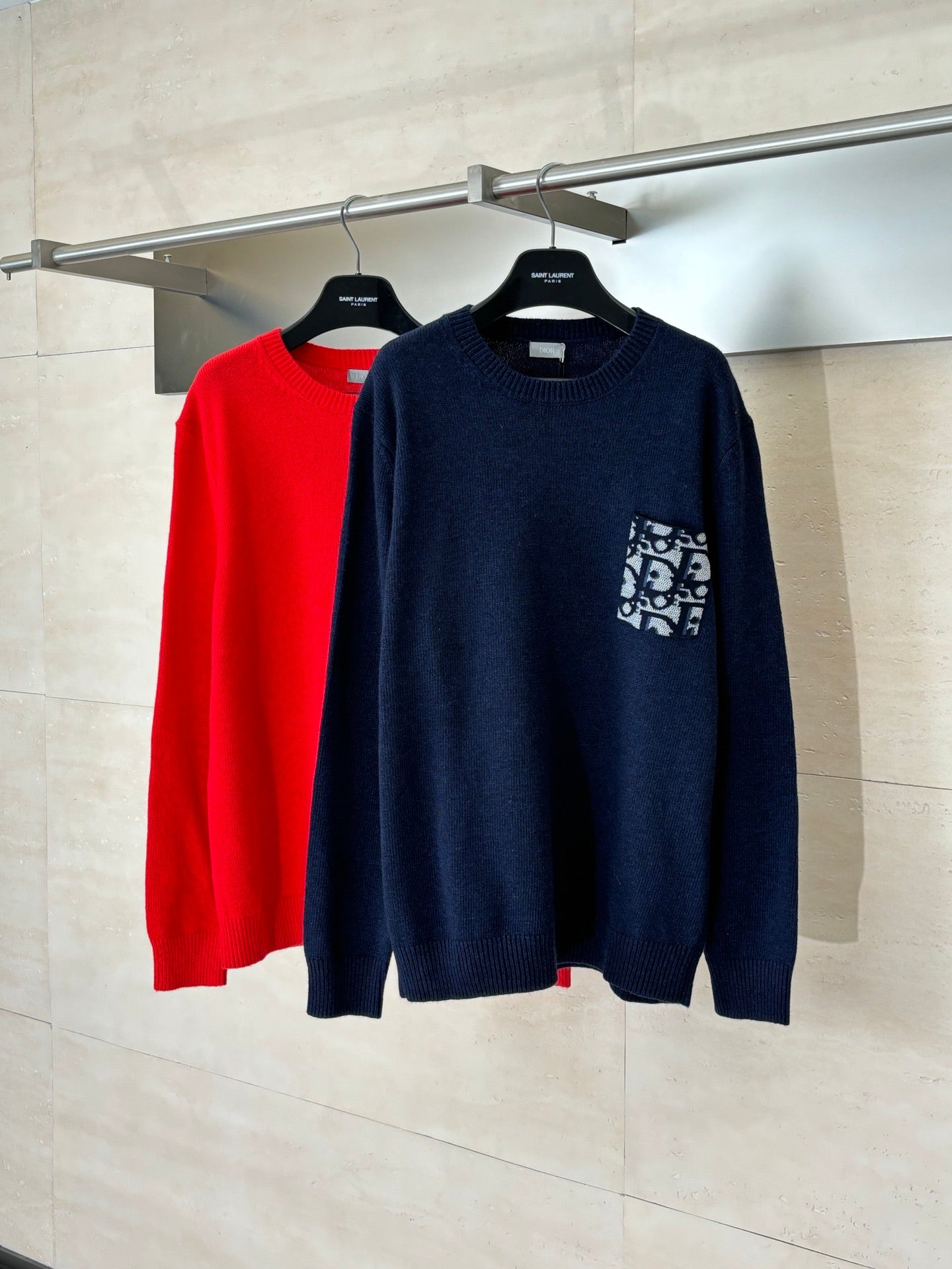 Navy knit sweater with chest logo patch, red sweater partially visible behind