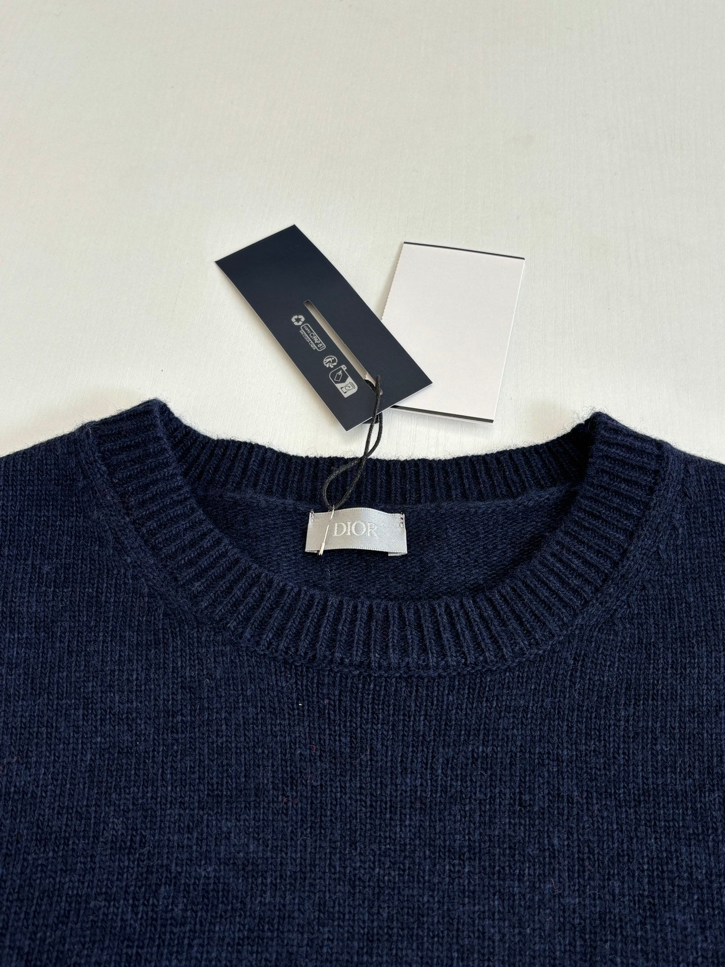 Navy crewneck knit sweater with Dior-branded tag at collar