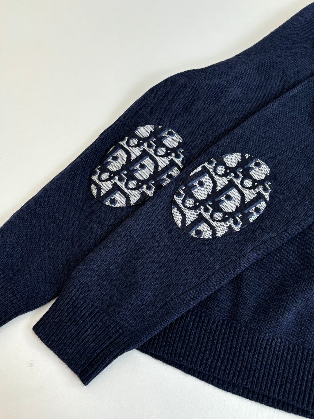 Navy sweater sleeve with logo graphic patch near cuff