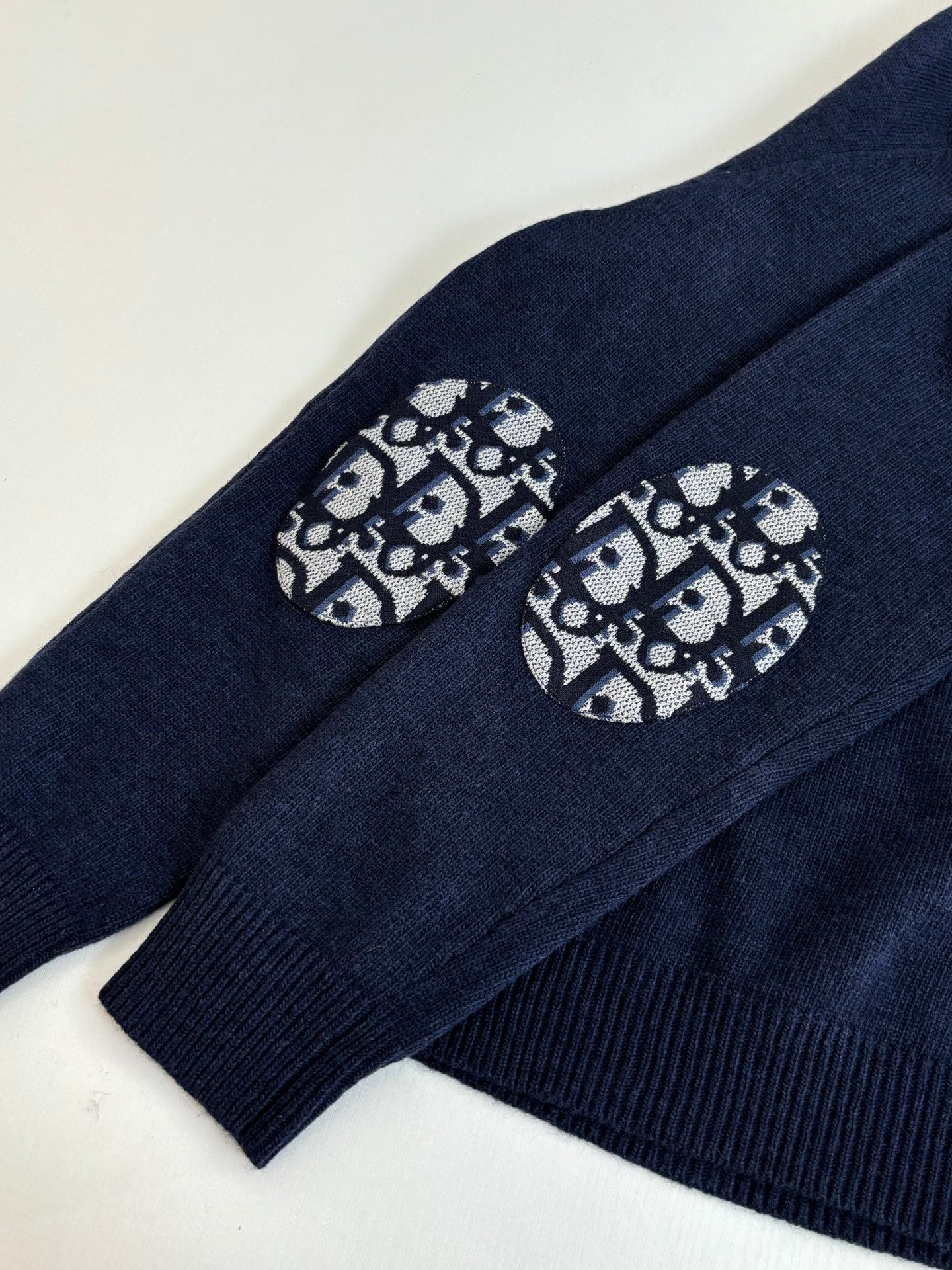 Navy sweater sleeve with logo graphic patch near cuff