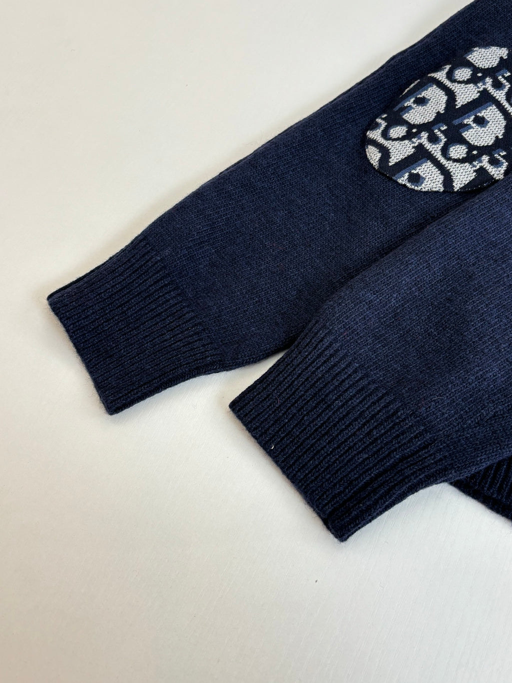 Navy ribbed knit sleeve cuffs with small logo graphic patch