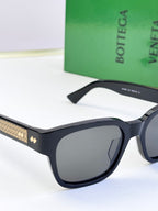 Bottega Veneta sunglasses close-up with dark frame and gold patterned temple