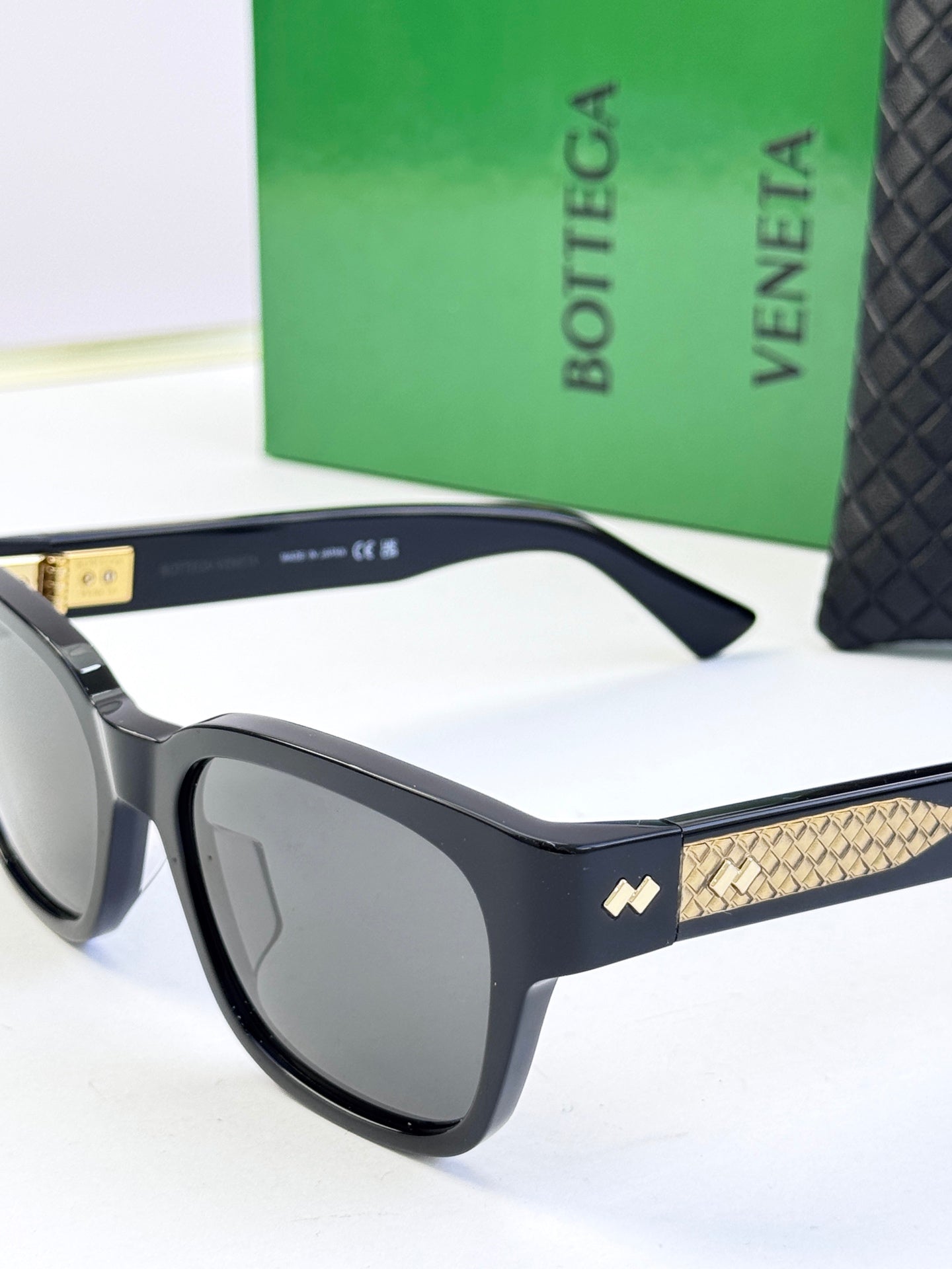 Bottega Veneta sunglasses side view with dark frame and gold patterned temple