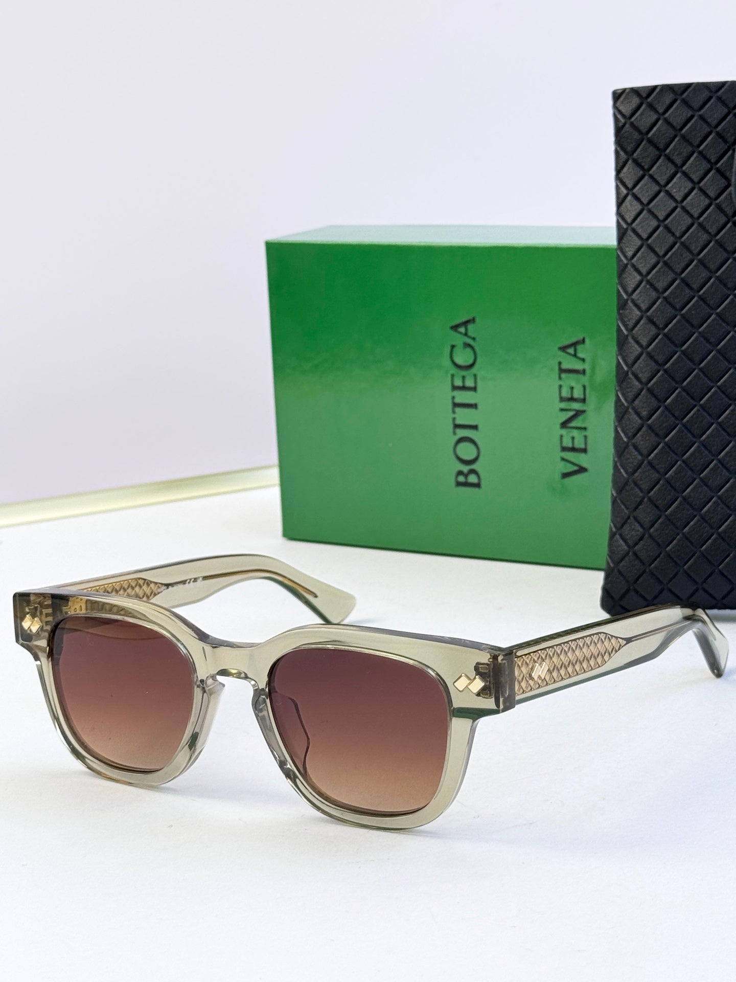 Sunglasses with light tan frames, textured gold temples, and brown tinted lenses