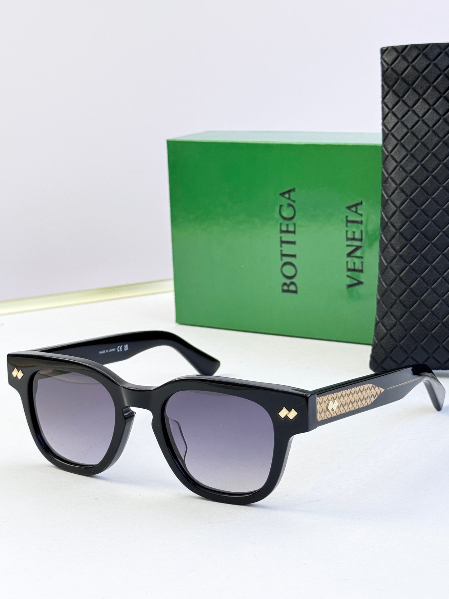 Sunglasses with black frames, textured gold temples, and tinted lenses