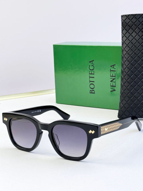 Sunglasses with black frames, textured gold temples, and tinted lenses