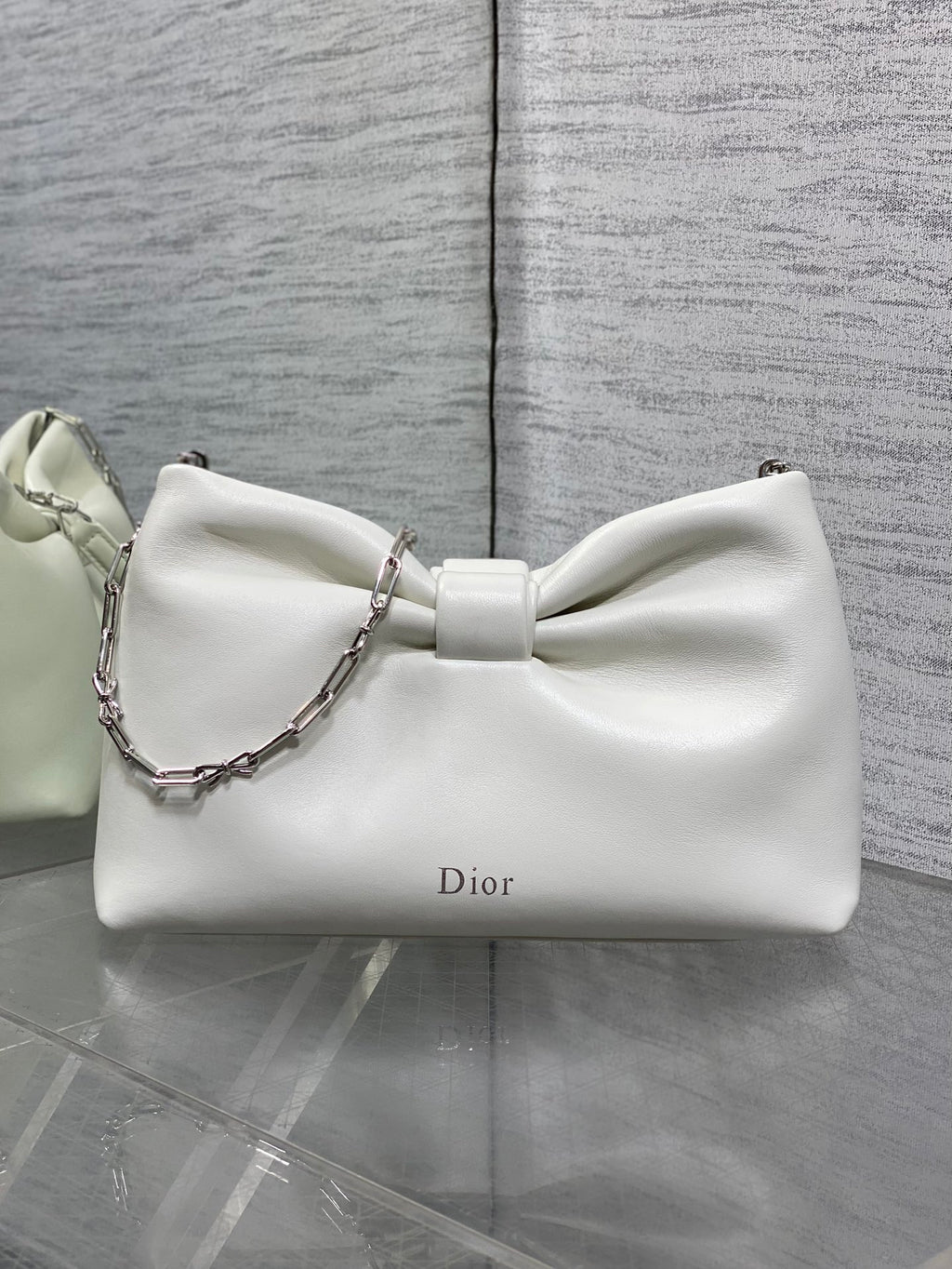 Ivory leather Dior bow handbag with silver chain strap and curved silhouette