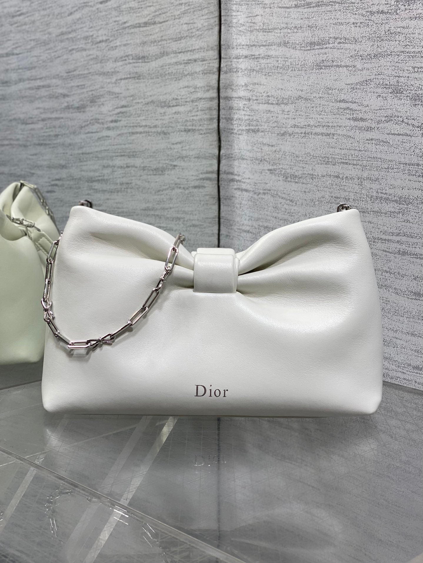 Ivory leather Dior bow handbag with silver chain strap and curved silhouette