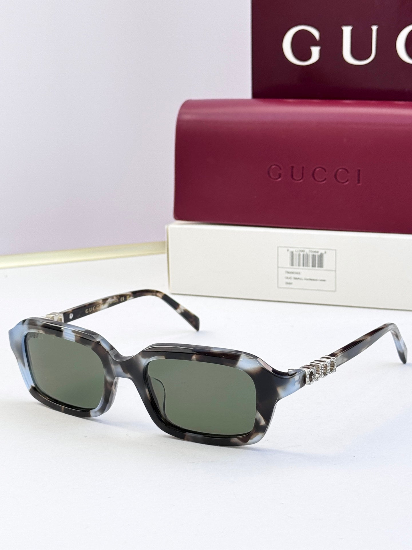 Mottled dark Gucci sunglasses with square frames and dark green-tinted lenses.