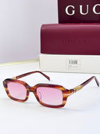 Tortoiseshell Gucci sunglasses with pink-tinted lenses and gold-toned decorative detail.
