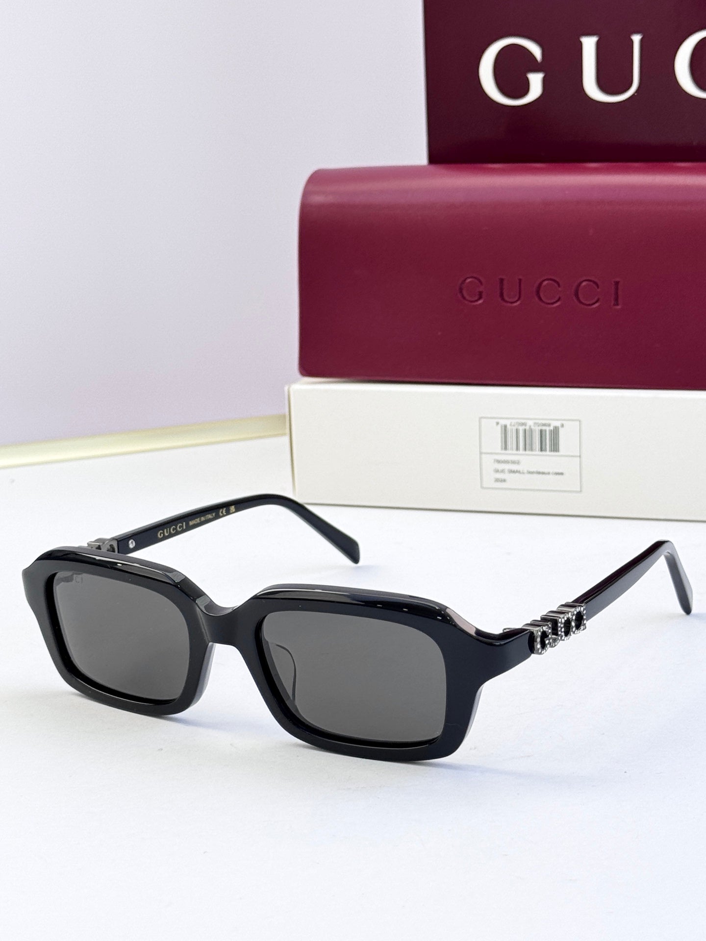 Black Gucci sunglasses with square frames and dark lenses, with jeweled metal detail on arms.