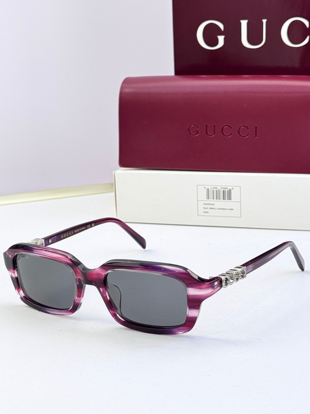 Purple Gucci sunglasses with oversized square frames and dark purple lenses.