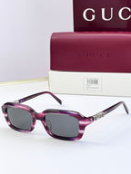 Purple Gucci sunglasses with oversized square frames and dark purple lenses.