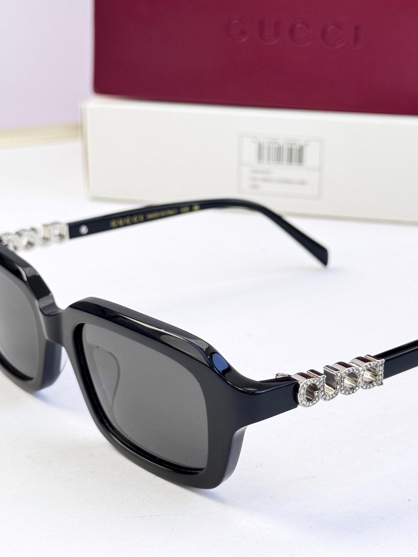 Black Gucci sunglasses with dark lenses and rhinestone chain detail on the arm.