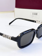 Black Gucci sunglasses with jeweled metal strap detail on the temple.