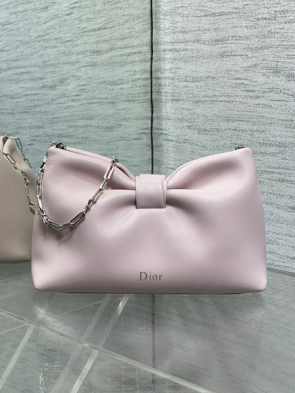 Light pink Dior bow clutch bag with chain strap and front logo