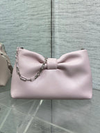 Light pink Dior bow bag with chain strap and curved top silhouette
