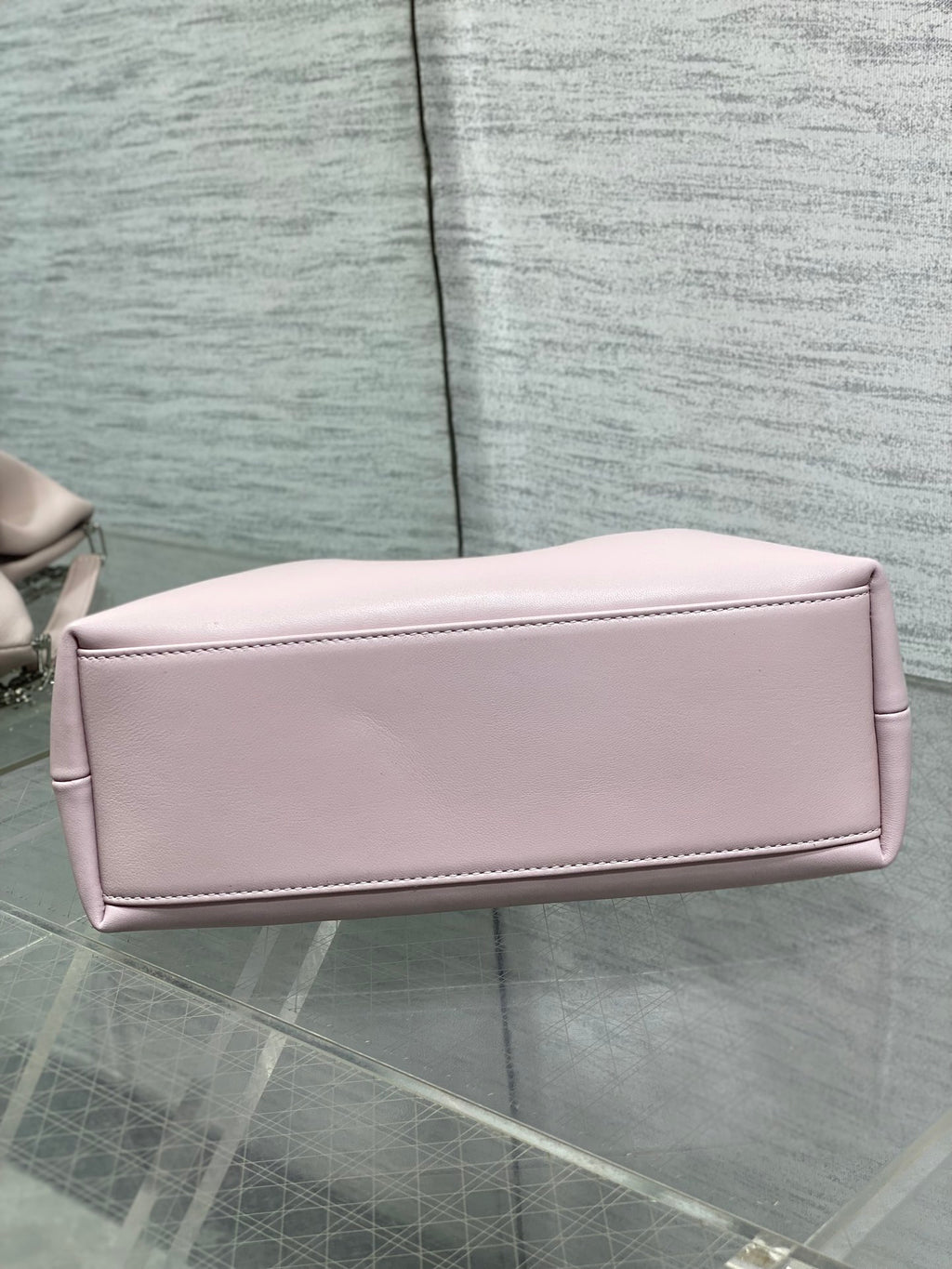 Light pink Dior bow bag side profile with top zipper and smooth finish
