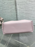 Light pink Dior bow bag side profile with top zipper and smooth finish