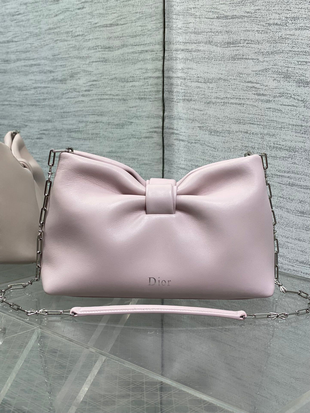 Light pink Dior bow bag with top handle and chain strap, logo on front