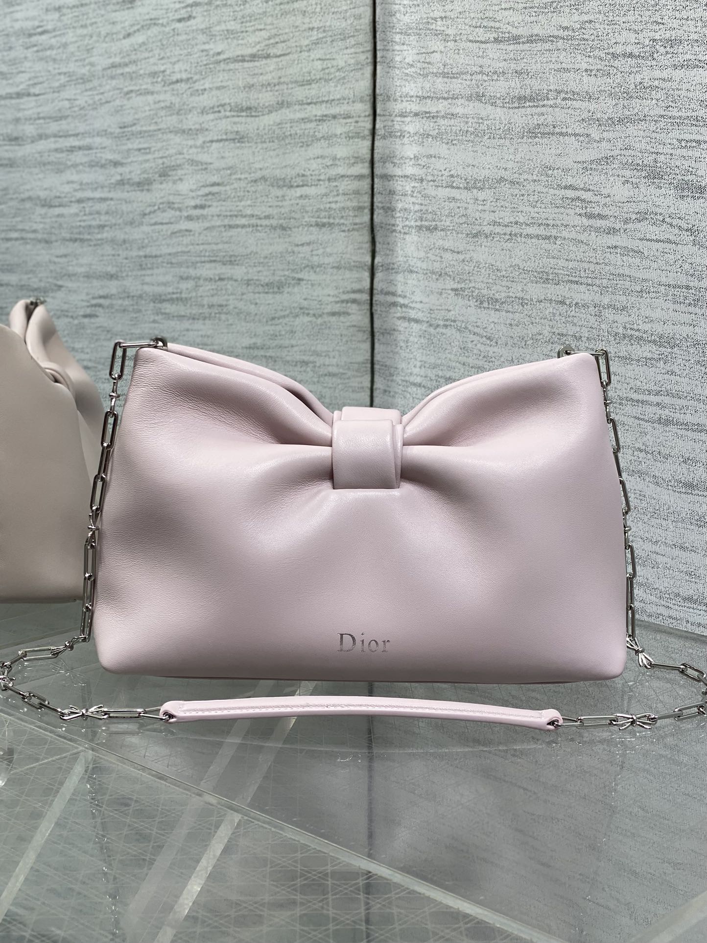 Light pink Dior bow bag with top handle and chain strap, logo on front