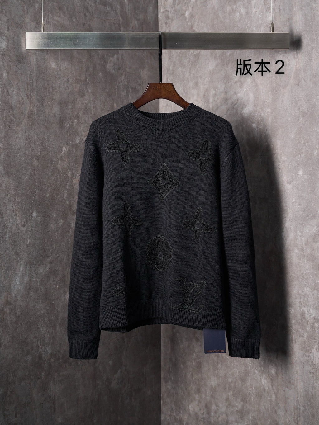 Black knit crewneck sweater with long sleeves and embossed monogram motifs