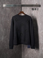 Black knit crewneck sweater with long sleeves and embossed monogram motifs
