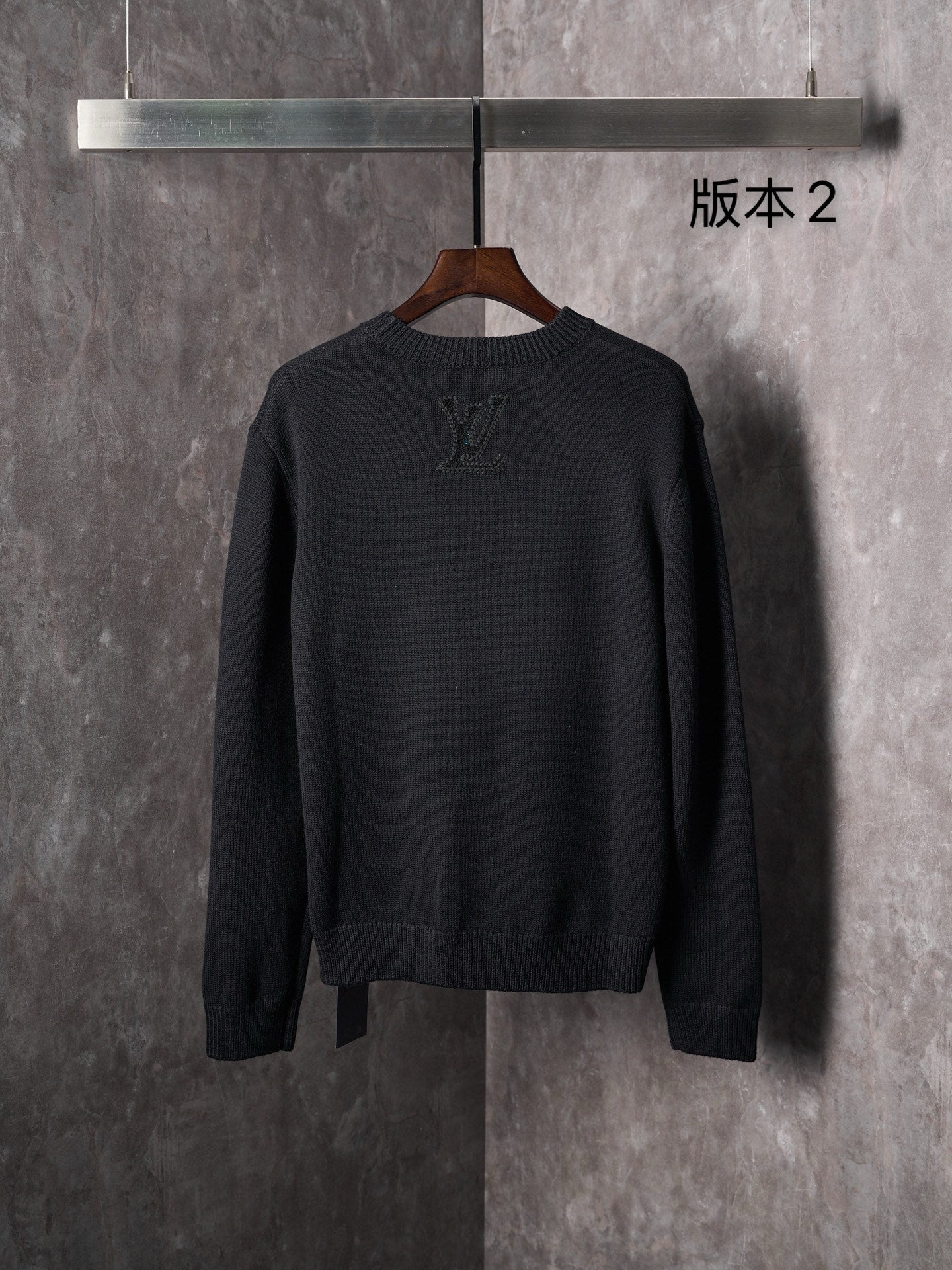 Black knit crewneck sweater back view with embossed monogram motifs
