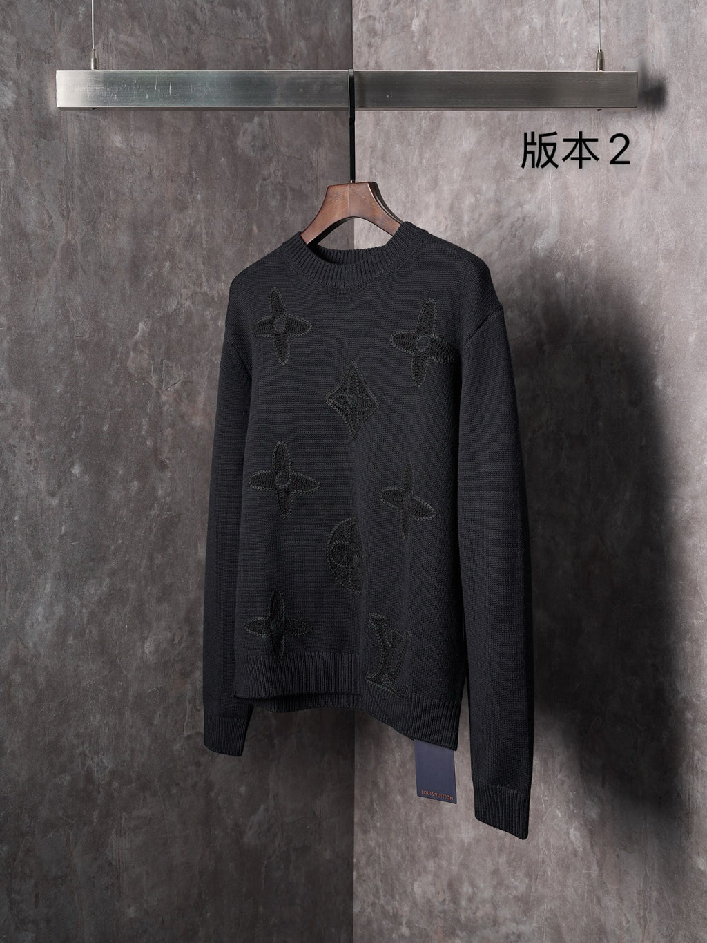 Black knit crewneck sweater front view with embossed monogram motifs