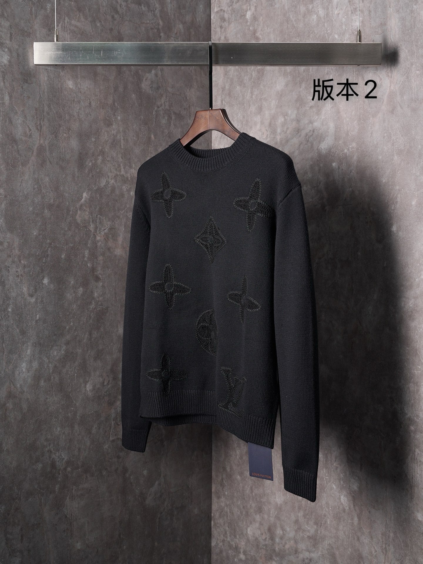 Black knit crewneck sweater front view with embossed monogram motifs