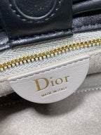 White Dior logo patch on black leather bag near gold zipper