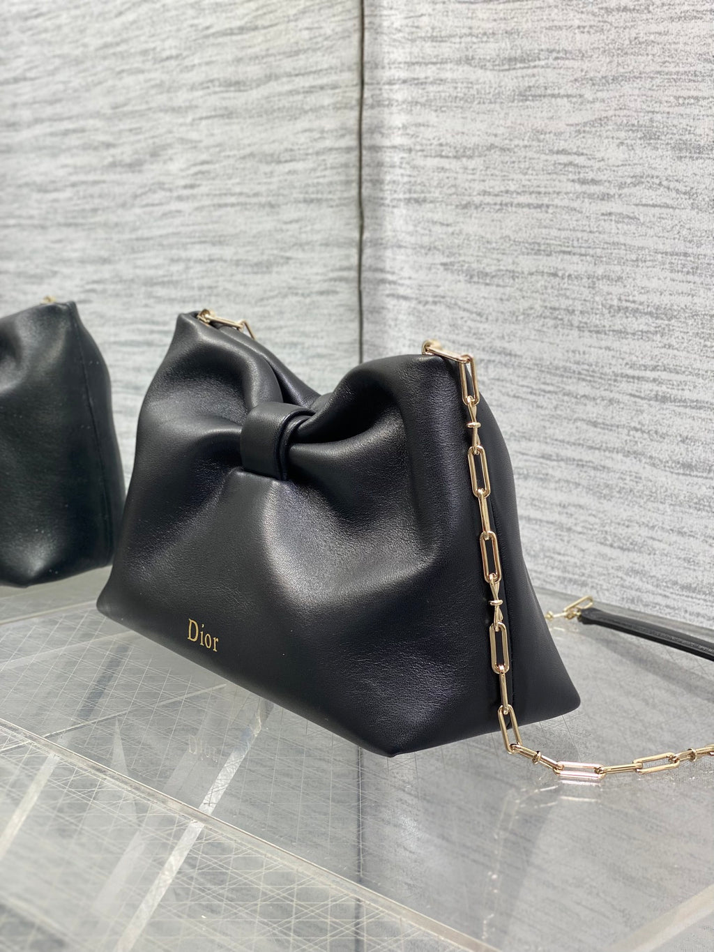 Black leather Dior bow bag with gold chain strap and Dior logo stamp
