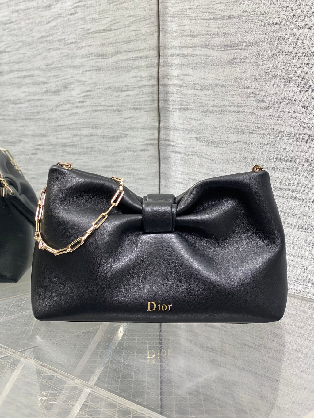 Black leather Dior bow bag with gold chain strap and front Dior logo