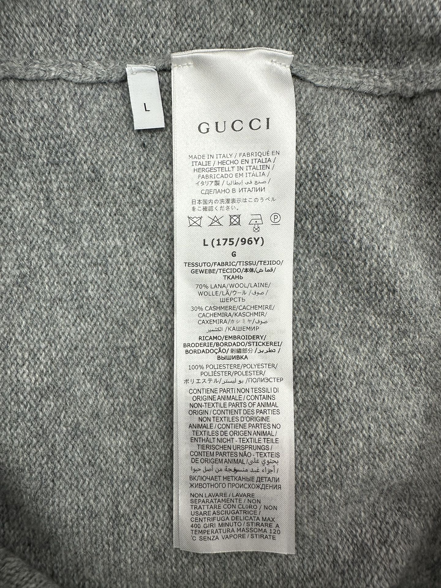Gucci clothing care and material tag on gray knit cardigan