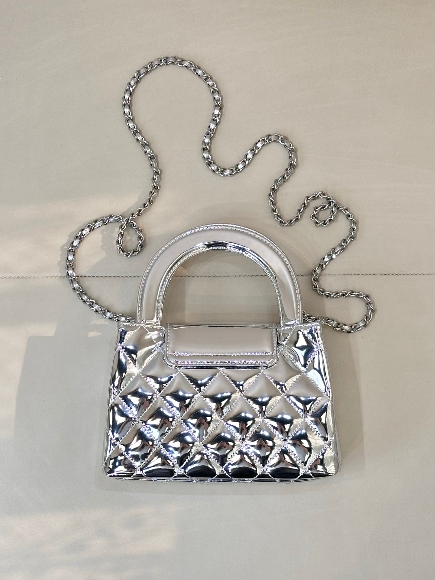 Chanel silver quilted mini bag front view with chain shoulder strap and curved handles