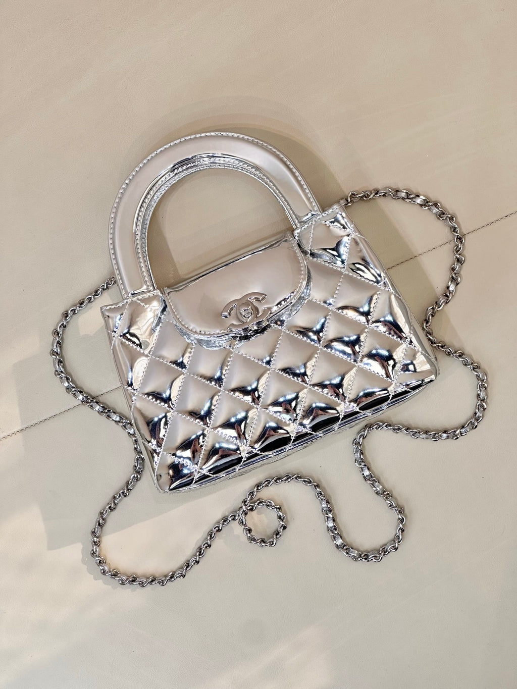 Chanel silver quilted mini bag angled view with top handle and chain shoulder strap